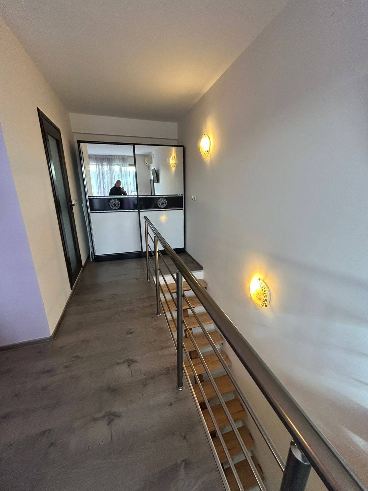 Современный интерьер: светлый коридор с лестницей и лампами Современный интерьер коридора с лестницей, стеклянной перегородкой и светильниками, идеальный для продажи недвижимости в Болгарии.