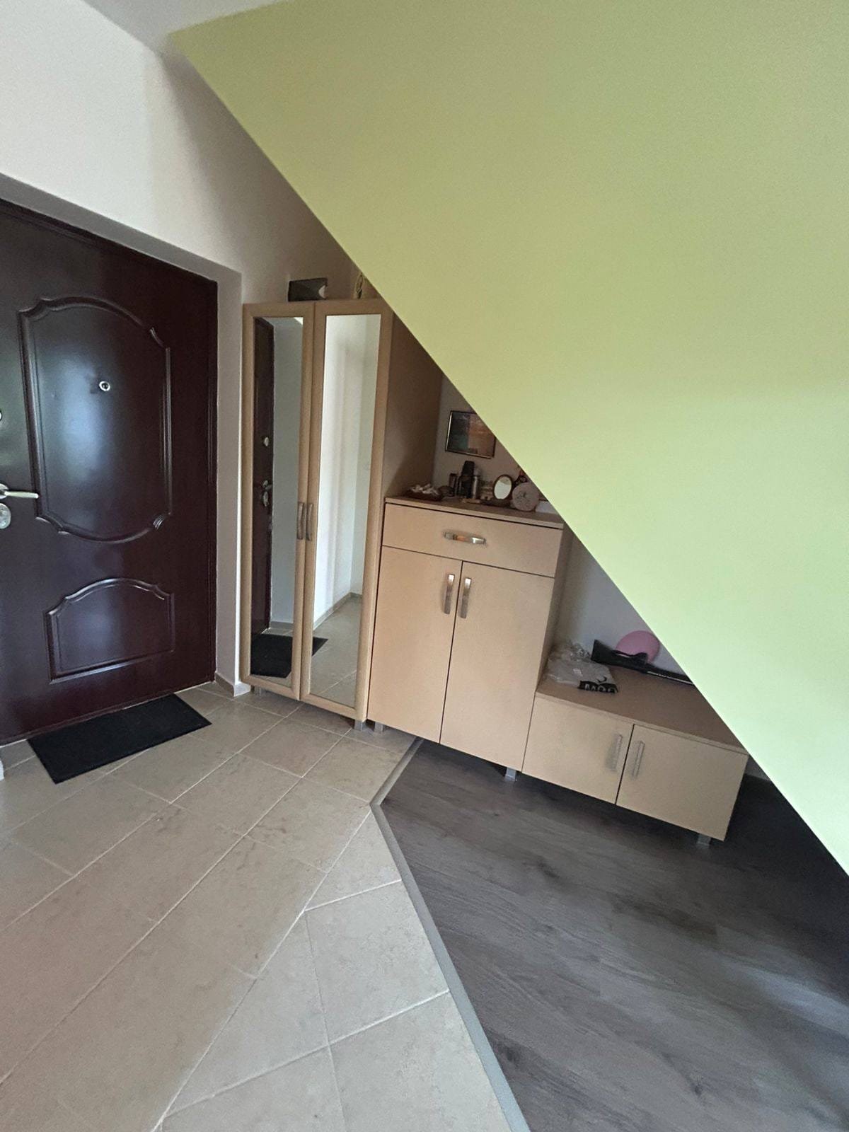 Современный интерьер коридора с зеркалом и шкафом Входное пространство с угловым шкафом и зеркалом, светлые тона, подходит для покупки недвижимости в Болгарии.