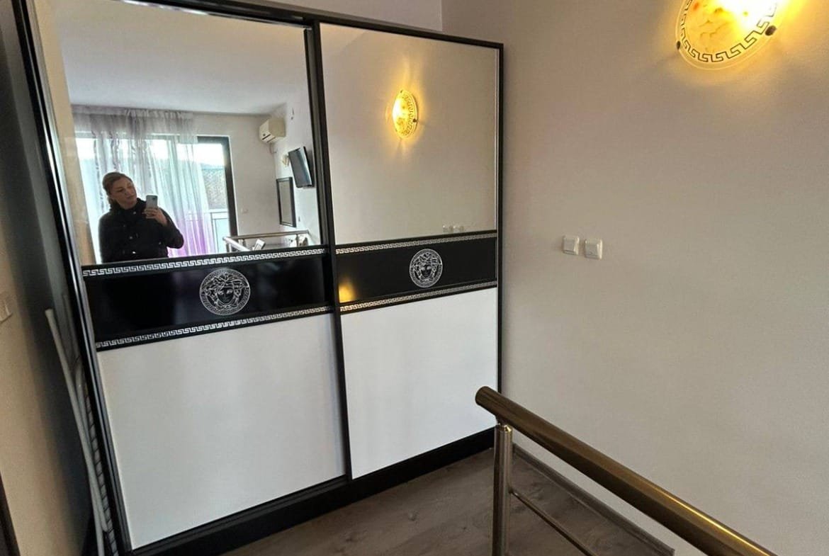 Современный коридор с раздвижными зеркальными дверями, металлическими перилами и светильниками, идеальный для продажи недвижимости в Болгарии.