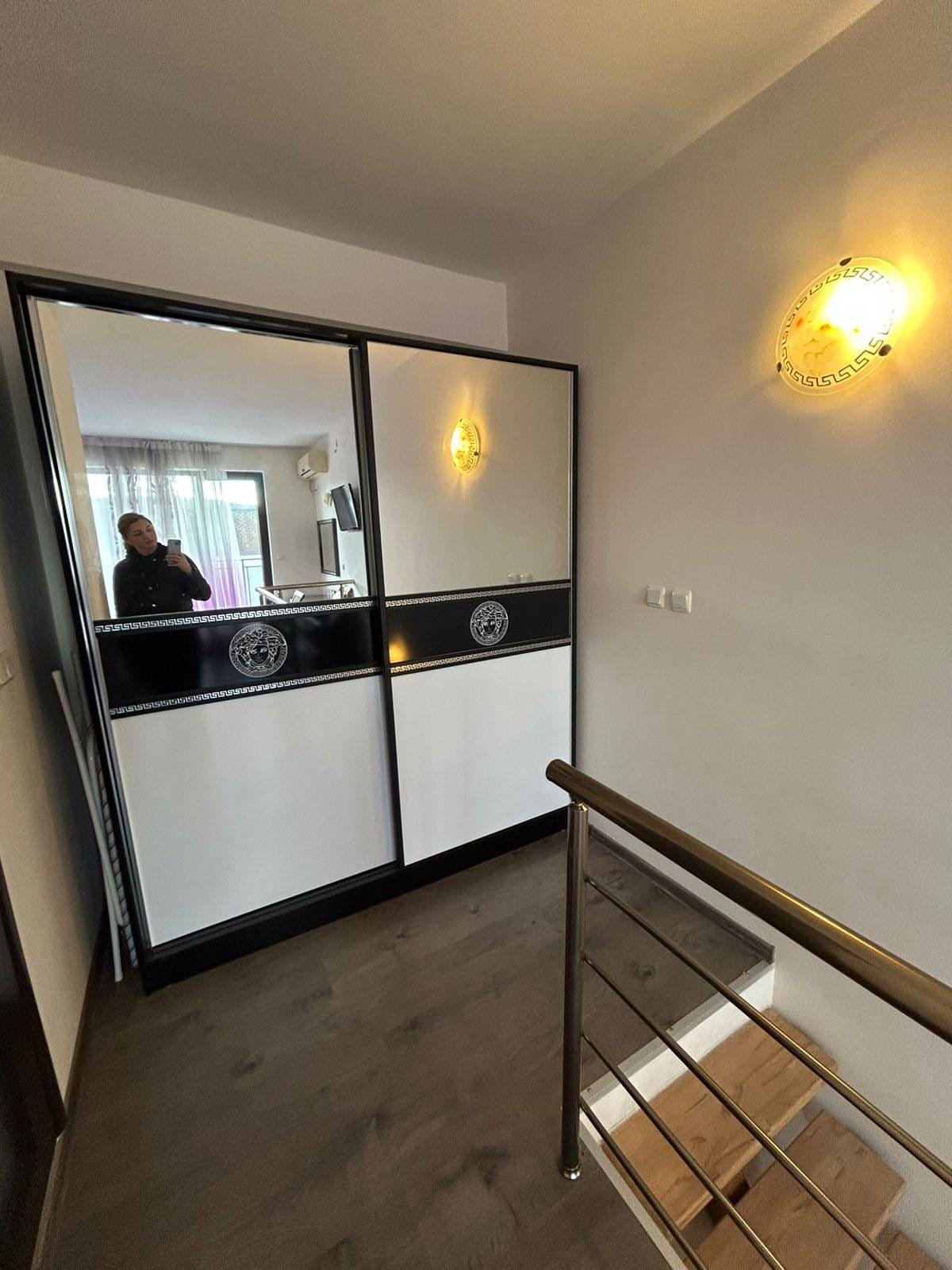 Современный интерьер прихожей с зеркальным шкафом и освещением Современный коридор с раздвижными зеркальными дверями, металлическими перилами и светильниками, идеальный для продажи недвижимости в Болгарии.