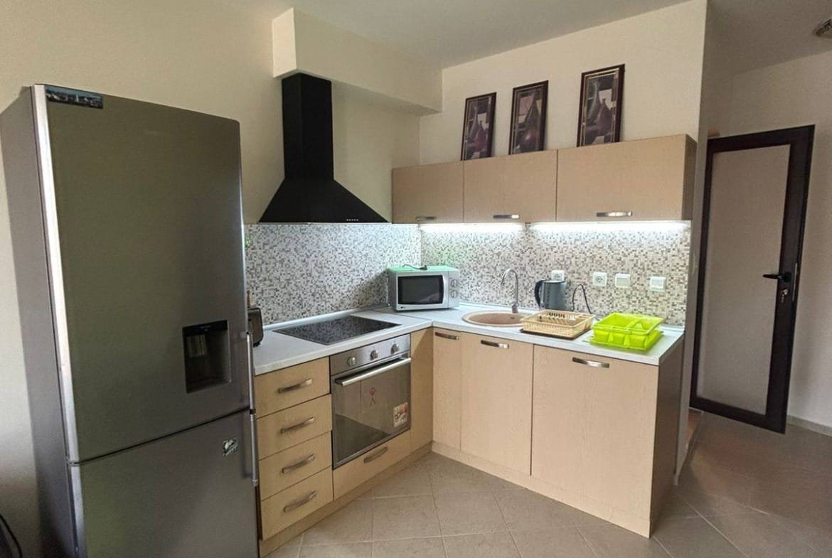 Современная кухня в квартире в Болгарии, со встроенной техникой и светлыми шкафами, идеально подходит для жизни и отдыха.