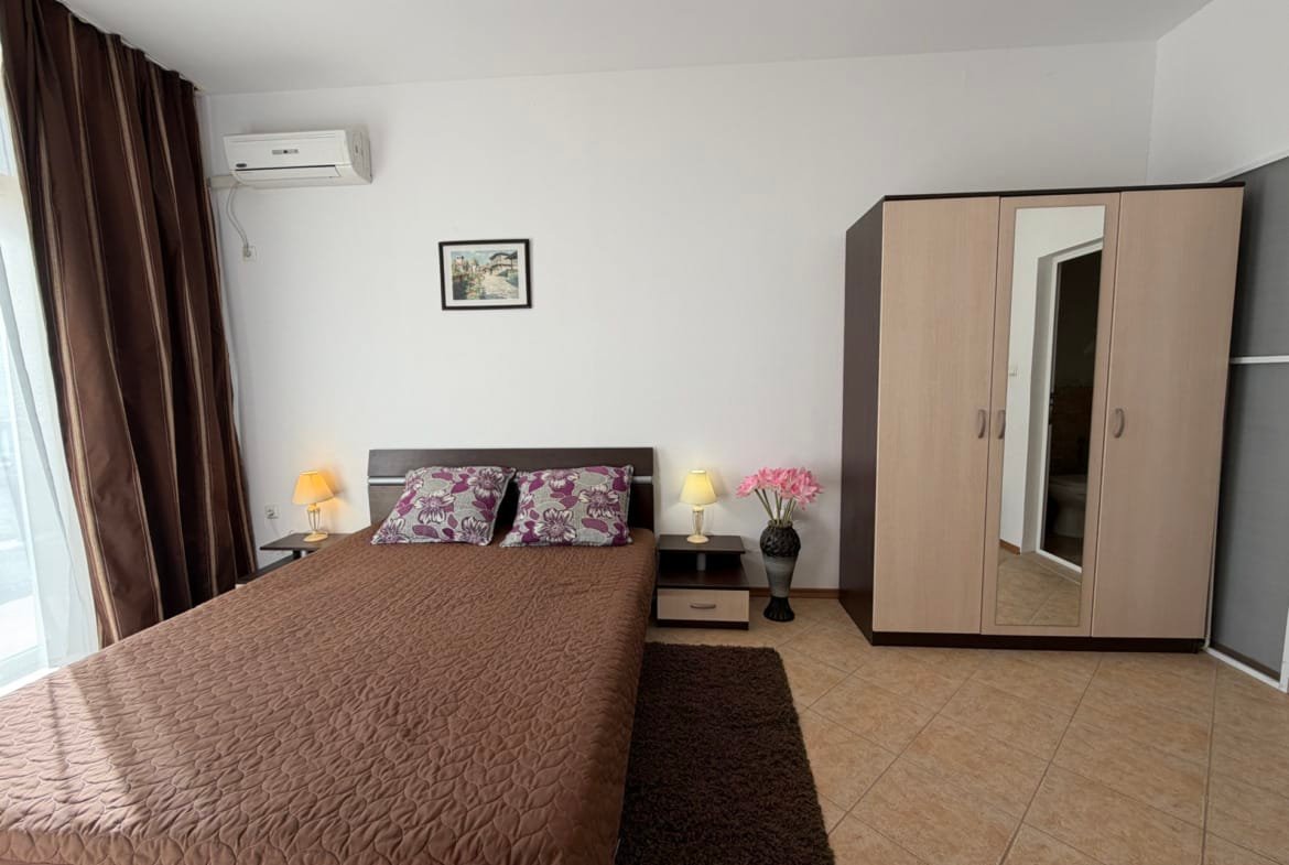 Современная спальня с двуспальной кроватью, шкафом и декоративными элементами, подходит для покупки недвижимости в Болгарии.