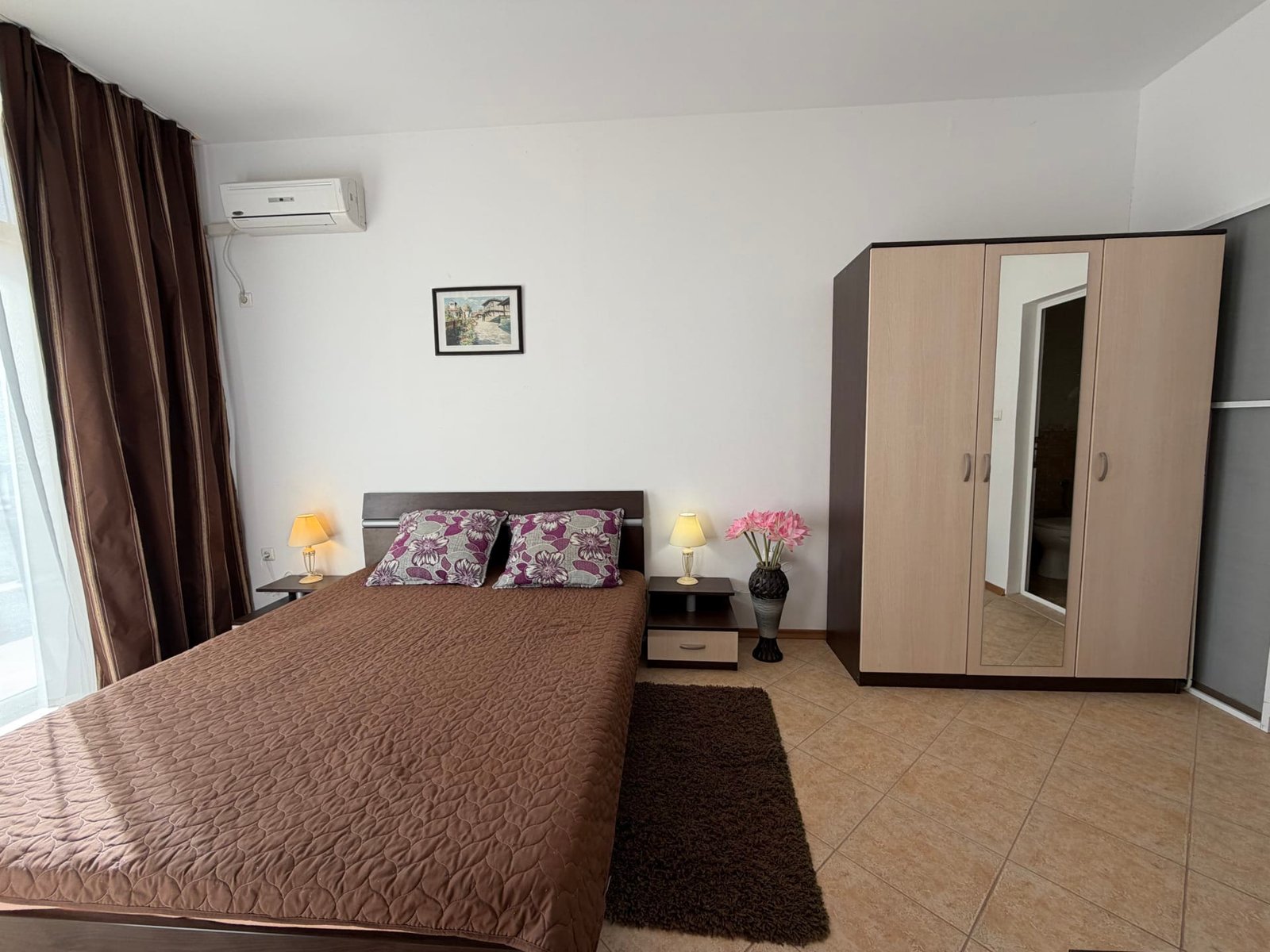 Современная спальня с двуспальной кроватью, шкафом и декоративными элементами, подходит для покупки недвижимости в Болгарии.