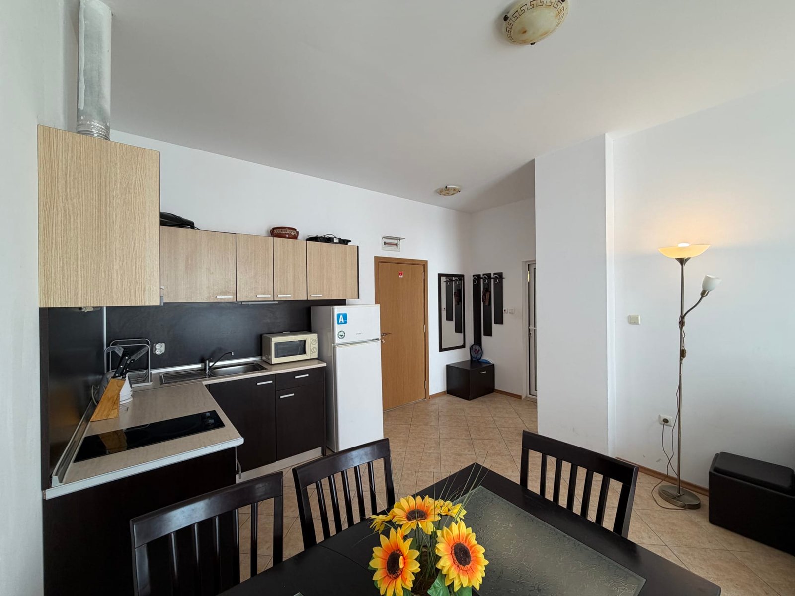 Современная кухня-студия с обеденным столом, техникой и яркими цветами, подходит для покупки недвижимости в Болгарии.