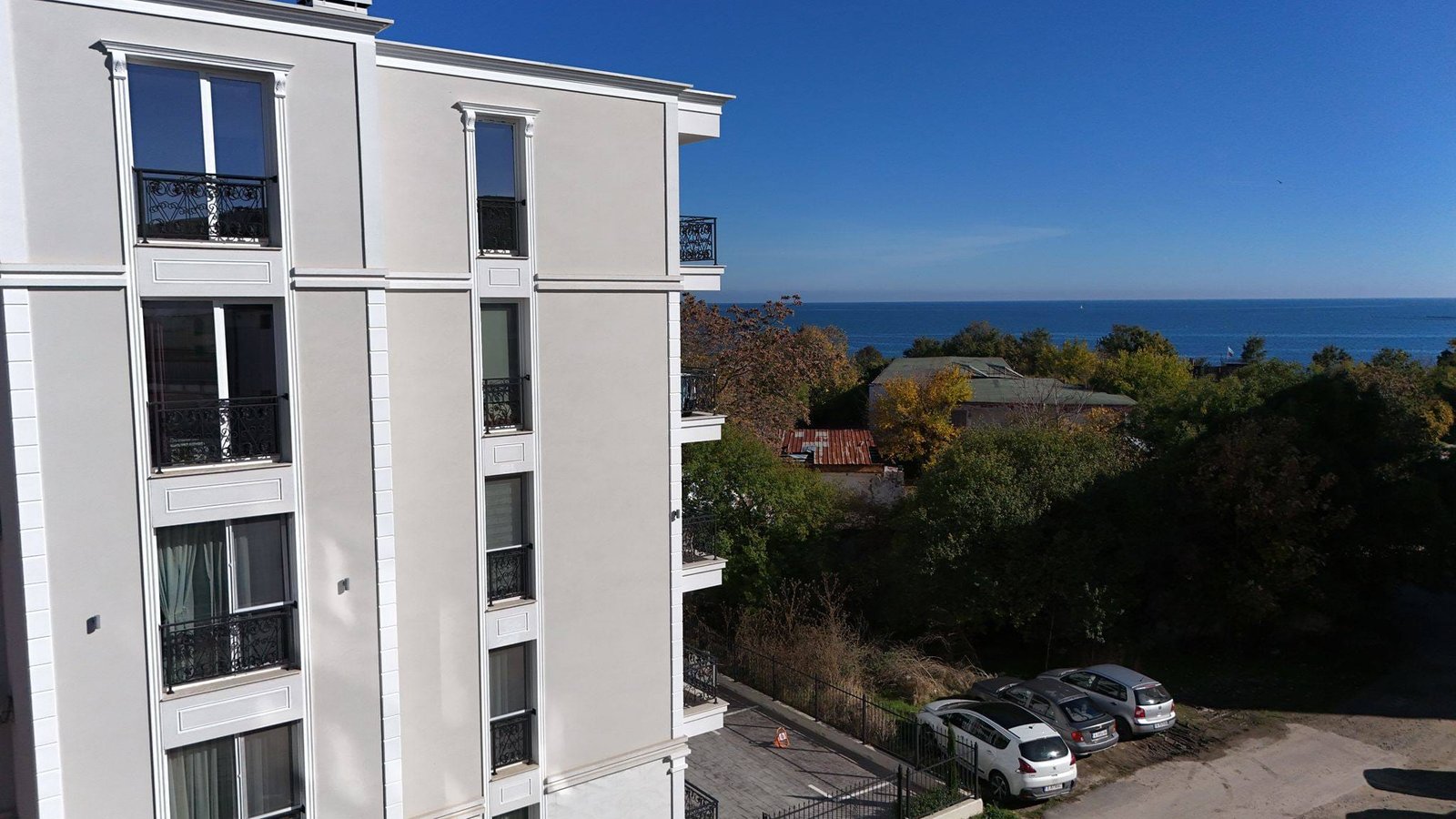 Современная студия в комплексе La Mer Gold с видом на море и зелёные насаждения, расположенная в светлом здании.