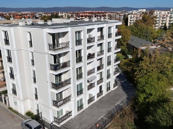 Современное здание с балконами, окруженное зеленью и городскими жилыми кварталами, расположенное в комплексе La Mer Gold.