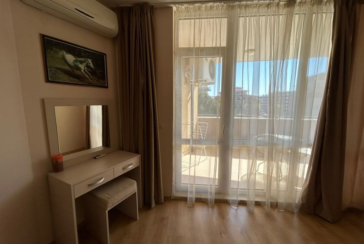 Современный интерьер квартиры в Болгарии с балконом, светлыми занавесками и уютной мебелью для комфортного проживания.