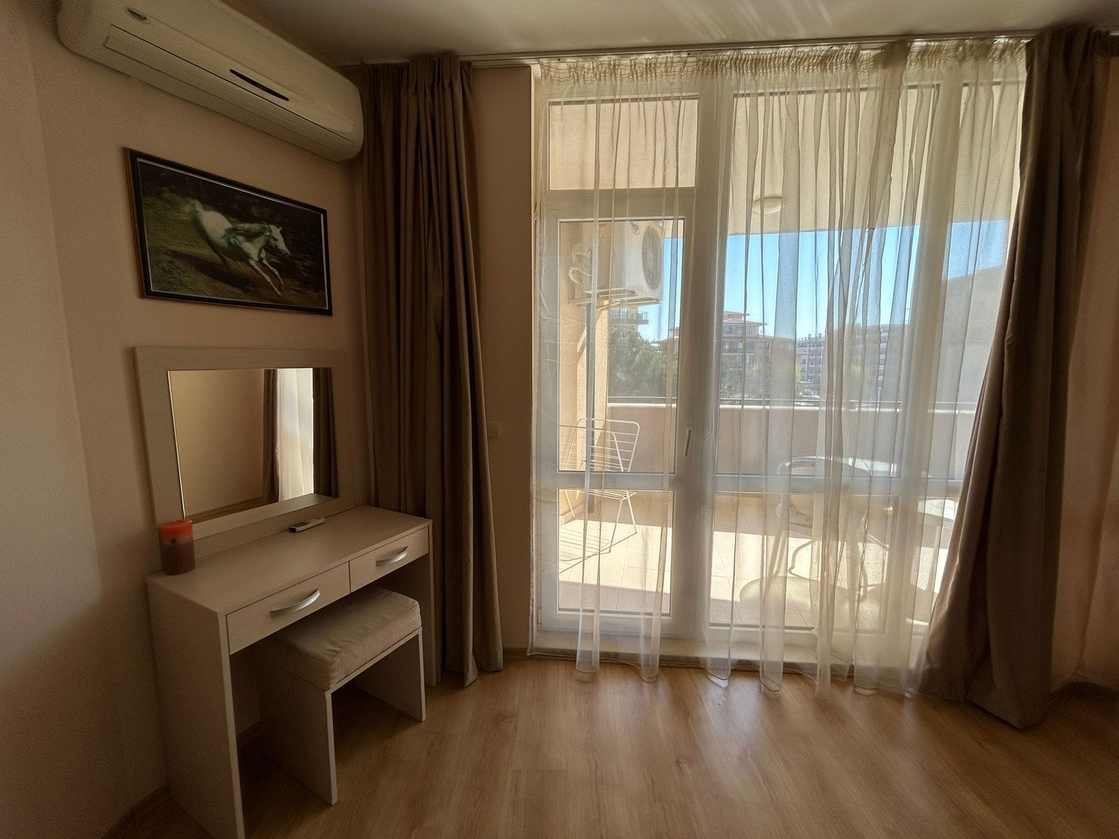 Современный интерьер квартиры с балконом и натуральным светом Современный интерьер квартиры в Болгарии с балконом, светлыми занавесками и уютной мебелью для комфортного проживания.