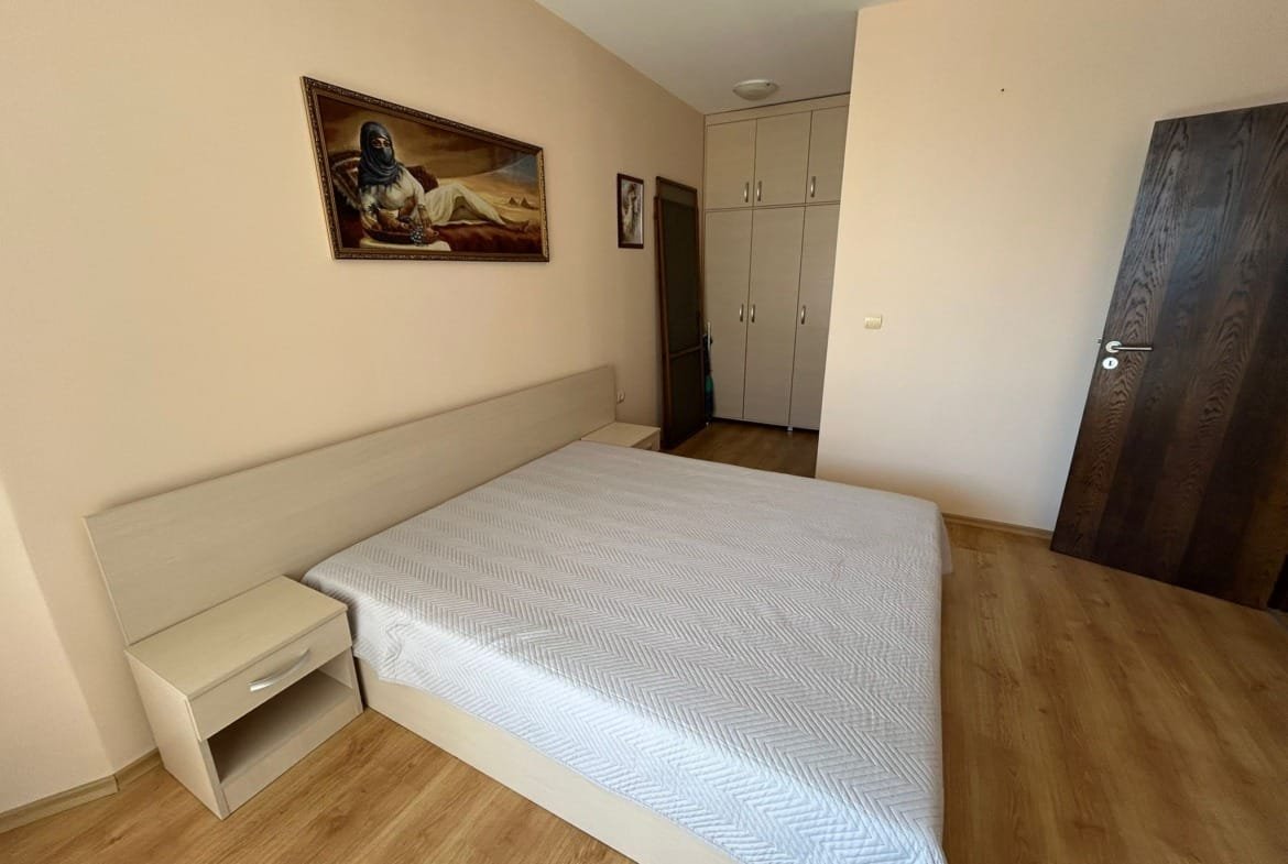 Современная спальня с двуспальной кроватью, светлыми стенами и шкафом, предназначенная для продажи недвижимости в Болгарии.