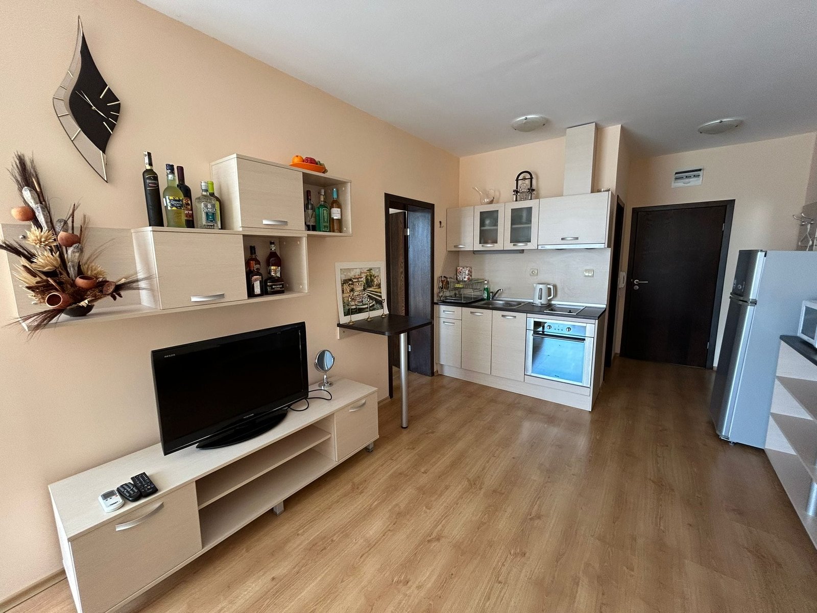 Современная кухня-гостиная: стильный интерьер и современная техника Современная кухня с минималистичной мебелью, телевизором, магазином и техникой для комфортного проживания в Болгарии.