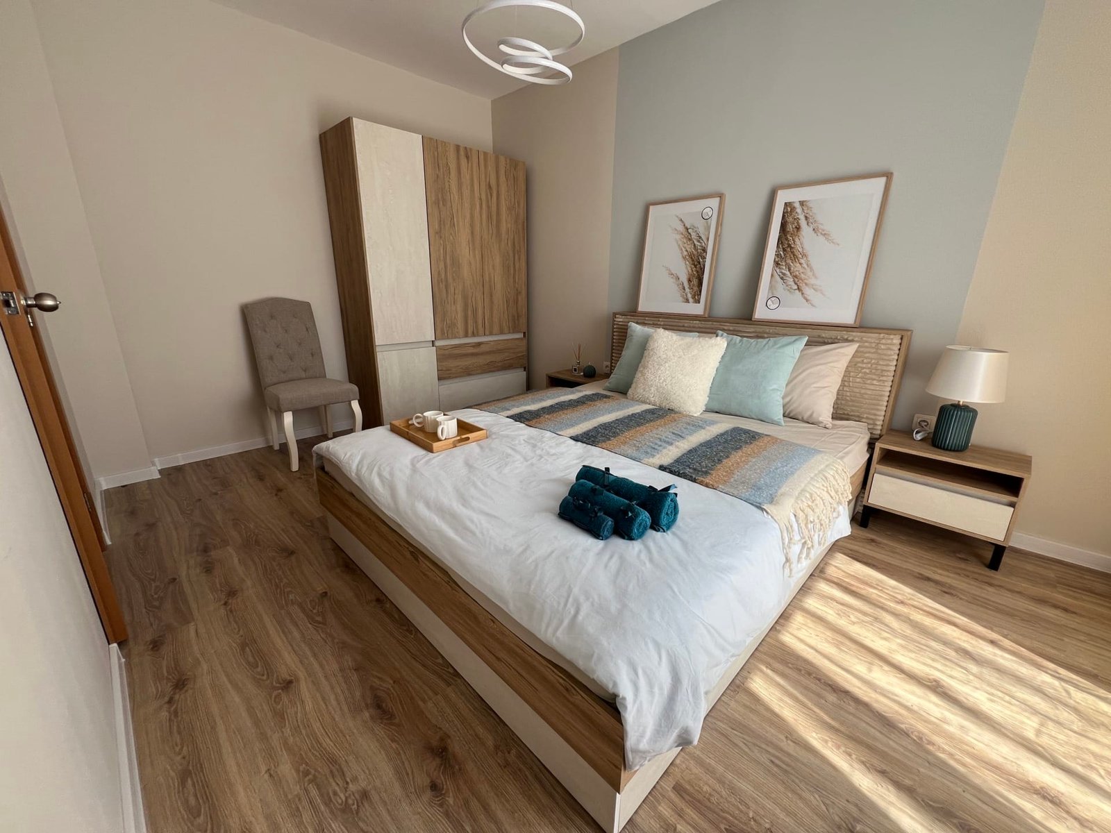 Современная спальня с двухспальной кроватью, натуральными тонами, светлым паркетом и стильной мебелью для комфортного проживания в Болгарии.