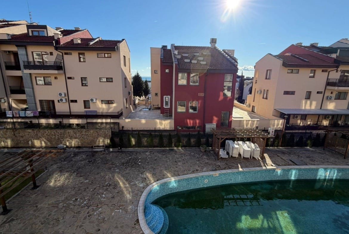 Комплекс современных жилых зданий с бассейном на фоне ясного неба в Болгарии, идеальный для покупки недвижимости.