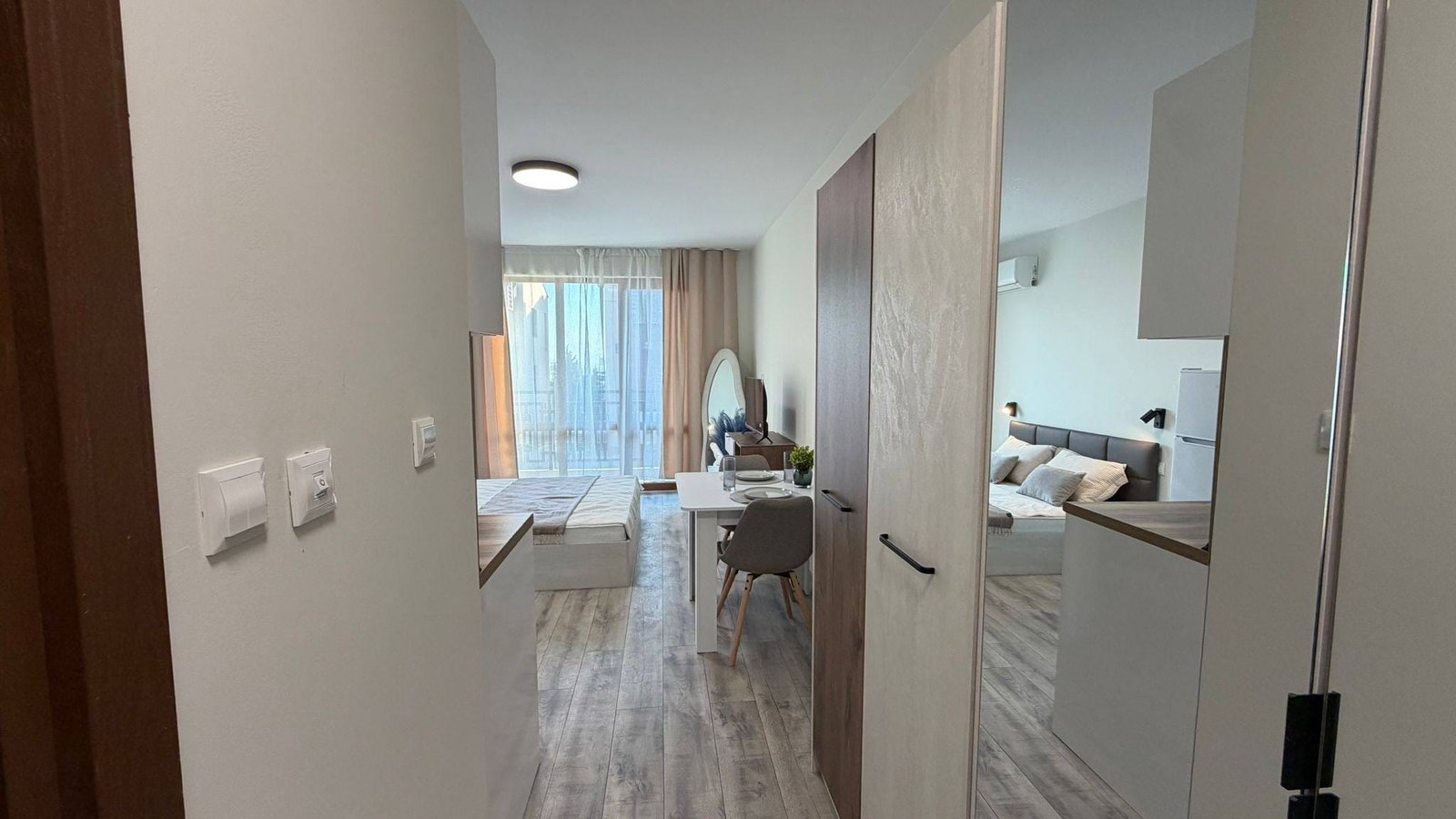 Современная квартира в Болгарии с открытой планировкой, стильной мебелью и большими окнами, обеспечивающими естественное освещение.