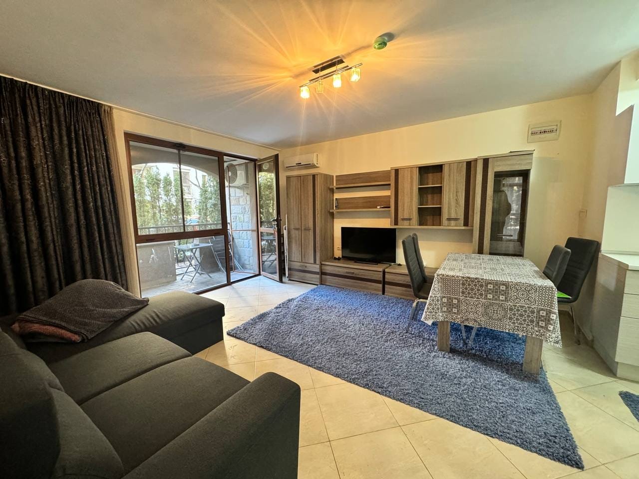 Современный интерьер квартиры в Болгарии с уютной гостиной, обеденным столом и выходом на балкон. Отличный вариант для покупки.