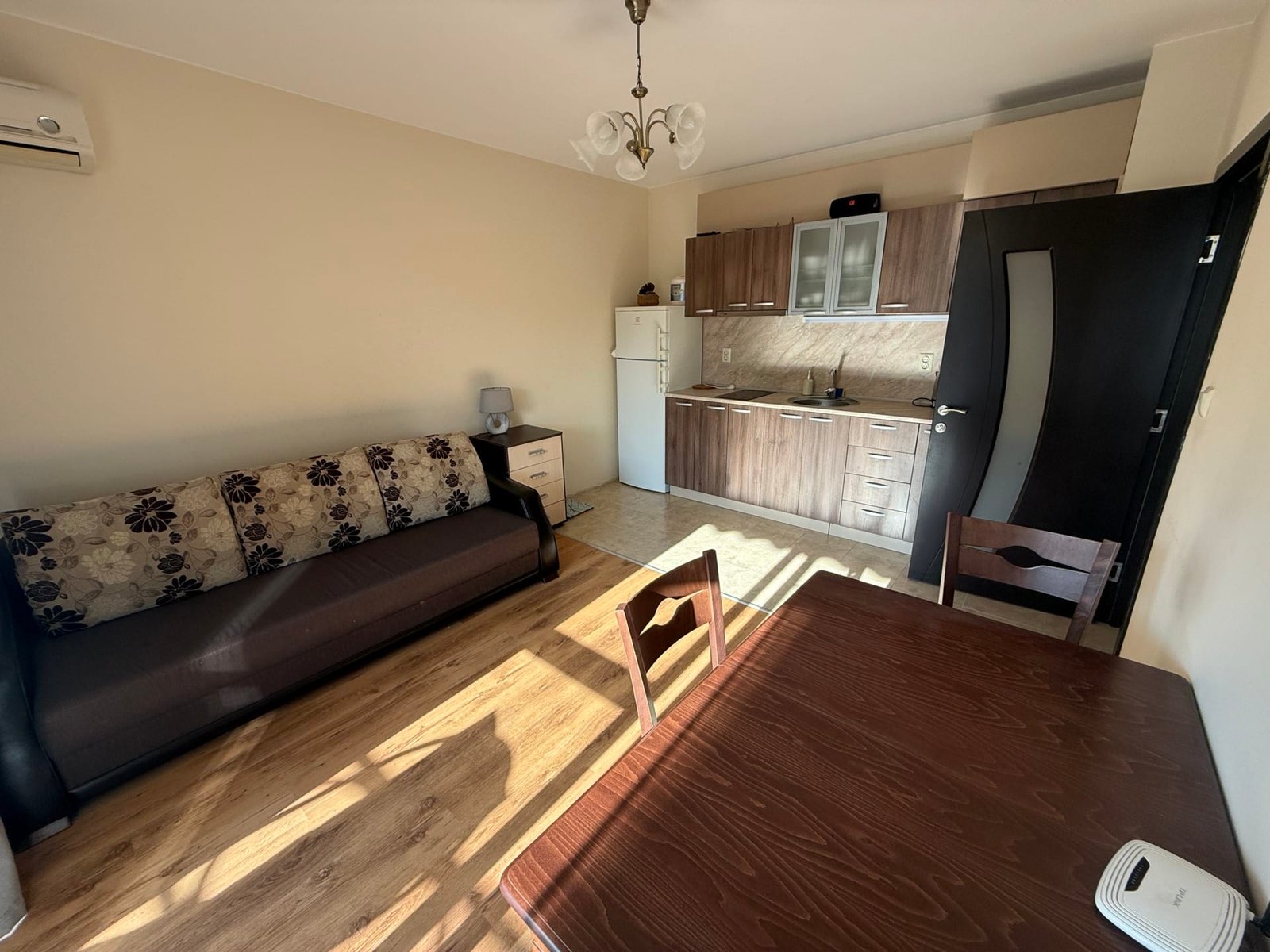 Современный интерьер квартиры в Болгарии с кухонной зоной, обеденным столом и мягким диваном. Отличное предложение для покупки.