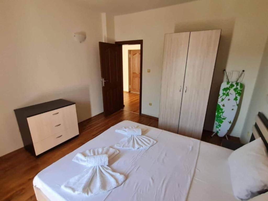 Светлая спальня с кроватью, шкафом и комодом, готовая к продаже недвижимости в Болгарии.