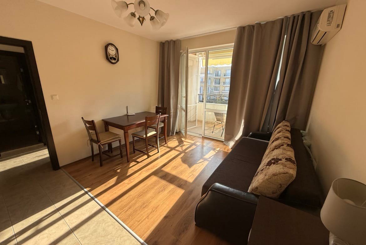 Современный интерьер квартиры в Болгарии с мебелью, балконом и ярким освещением, подходящий для продажи или аренды.