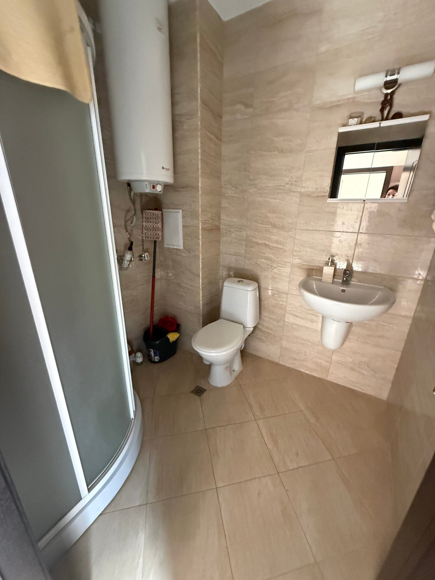 Современная ванная комната с душевой кабиной, унитазом и раковиной, оформленная в светлых тонах. Подходит для недвижимости в Болгарии.