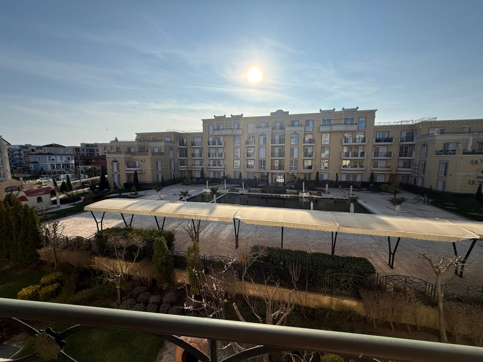 Современный жилой комплекс в Болгарии с солнечным двориком, ландшафтным дизайном и зоной для отдыха на фоне ясного неба.