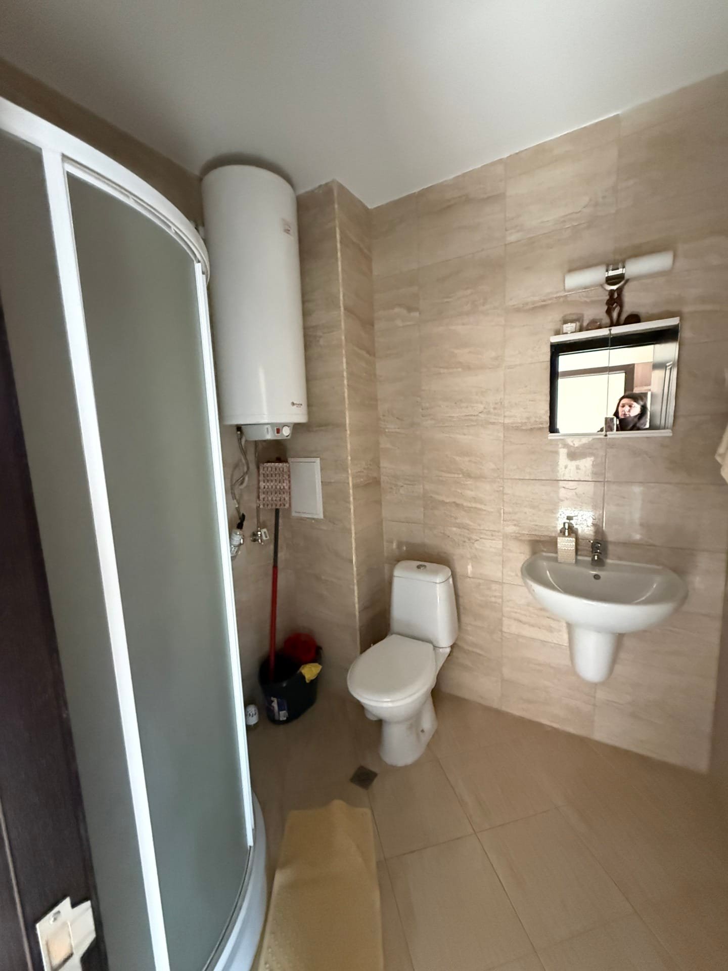 Современная ванная комната с душевой кабиной, унитазом и раковиной, оформленная в светлых тонах для продажи недвижимости в Болгарии.