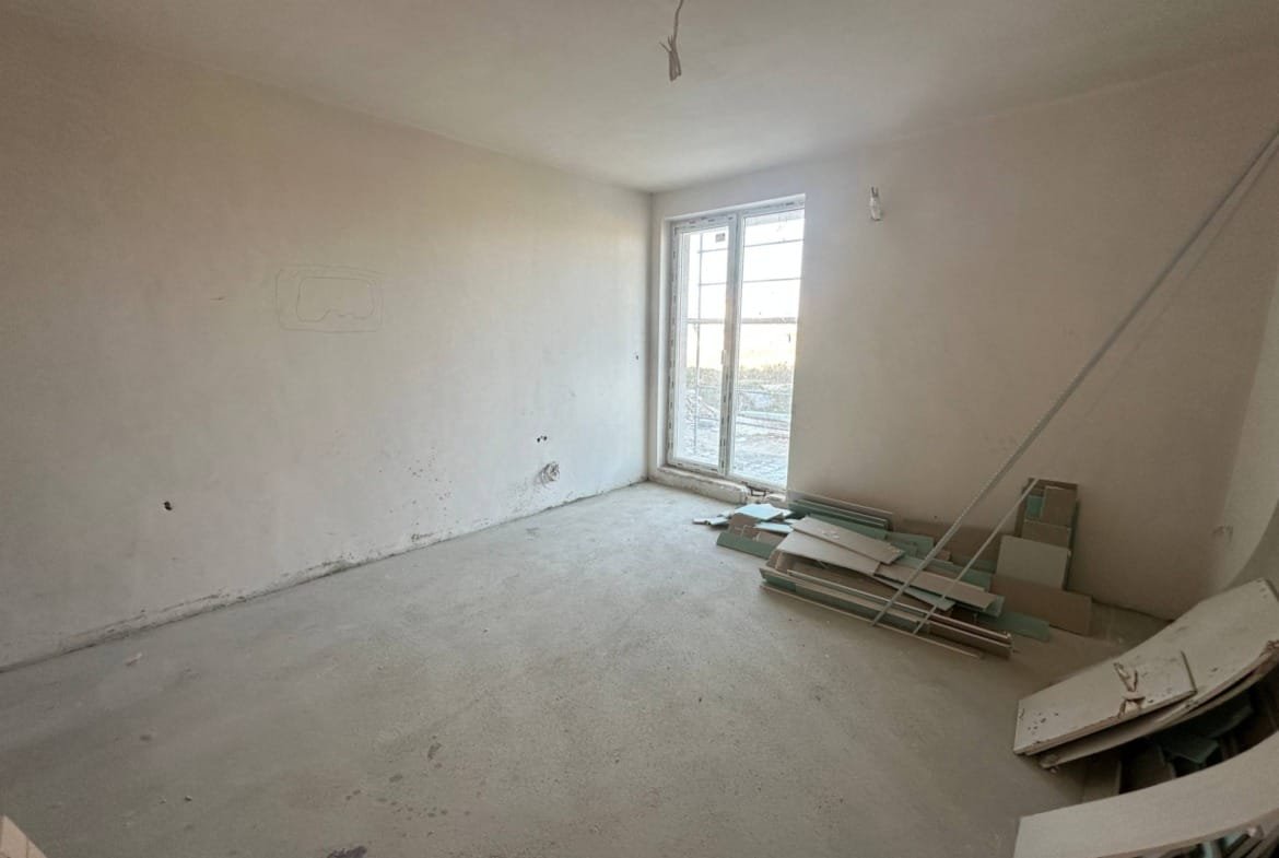 Светлое пустое помещение с окном, необработанные стены и строительные материалы на полу. Подходит для студии в "La Mer Gold".