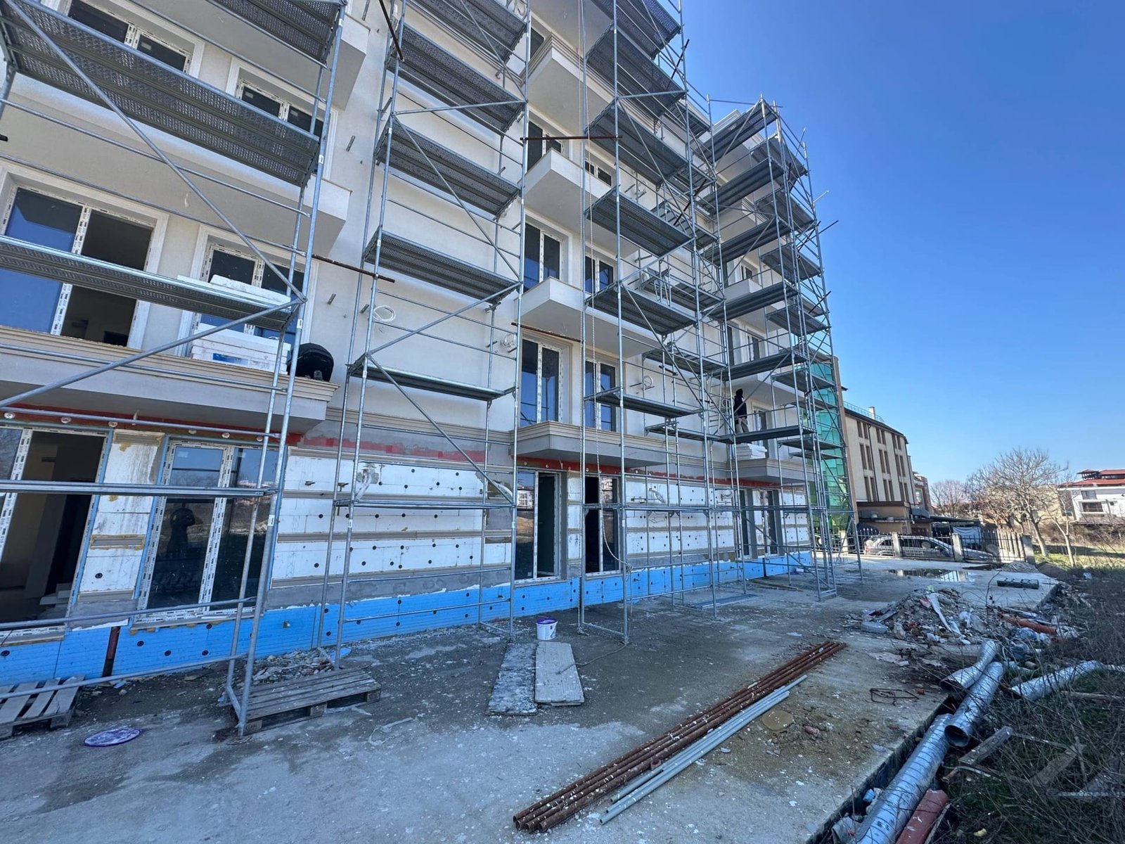 Строительство здания в комплексе La Mer Gold с строительными лесами, новыми окнами и завершением фасада.