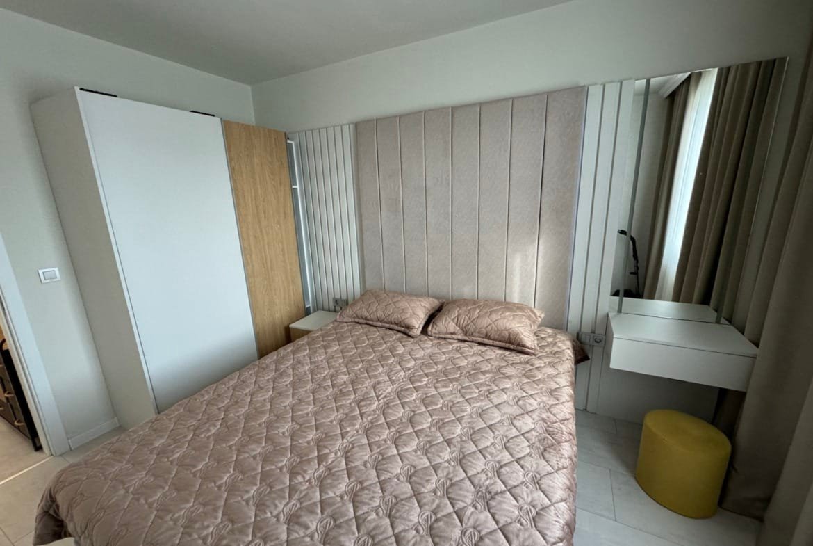 Современная спальня с двумя кроватями, стильным зеркалом и уютным освещением, идеально подходит для продажи недвижимости в Болгарии.