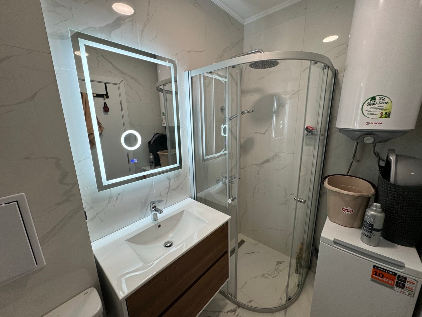 Современная ванная комната с зеркалом, душевой кабиной и стильно оформленной сантехникой для продажи недвижимости в Болгарии.