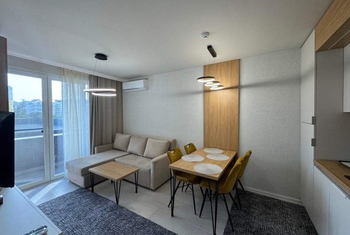 Современный интерьер квартиры в Болгарии с уютной гостиной, столовой и балконом, идеален для продажи и покупки недвижимости.