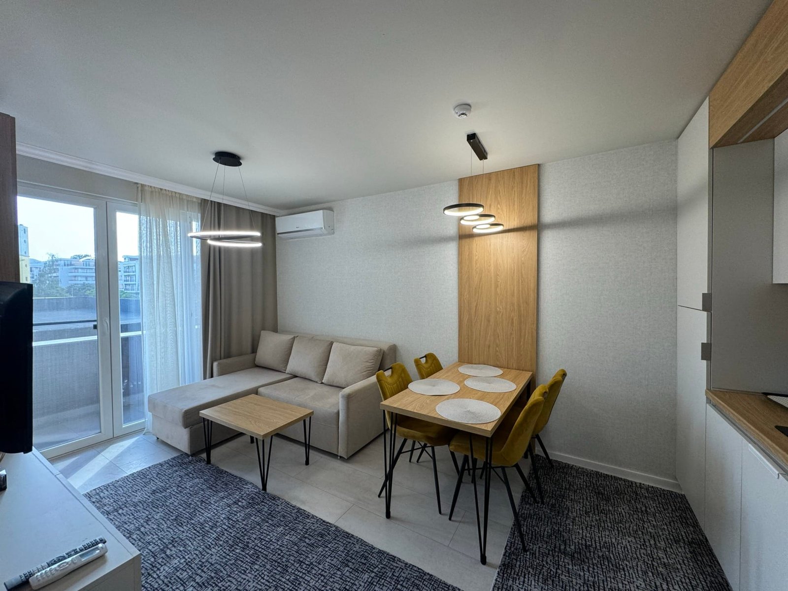 Современный интерьер квартиры в Болгарии с уютной гостиной, столовой и балконом, идеален для продажи и покупки недвижимости.