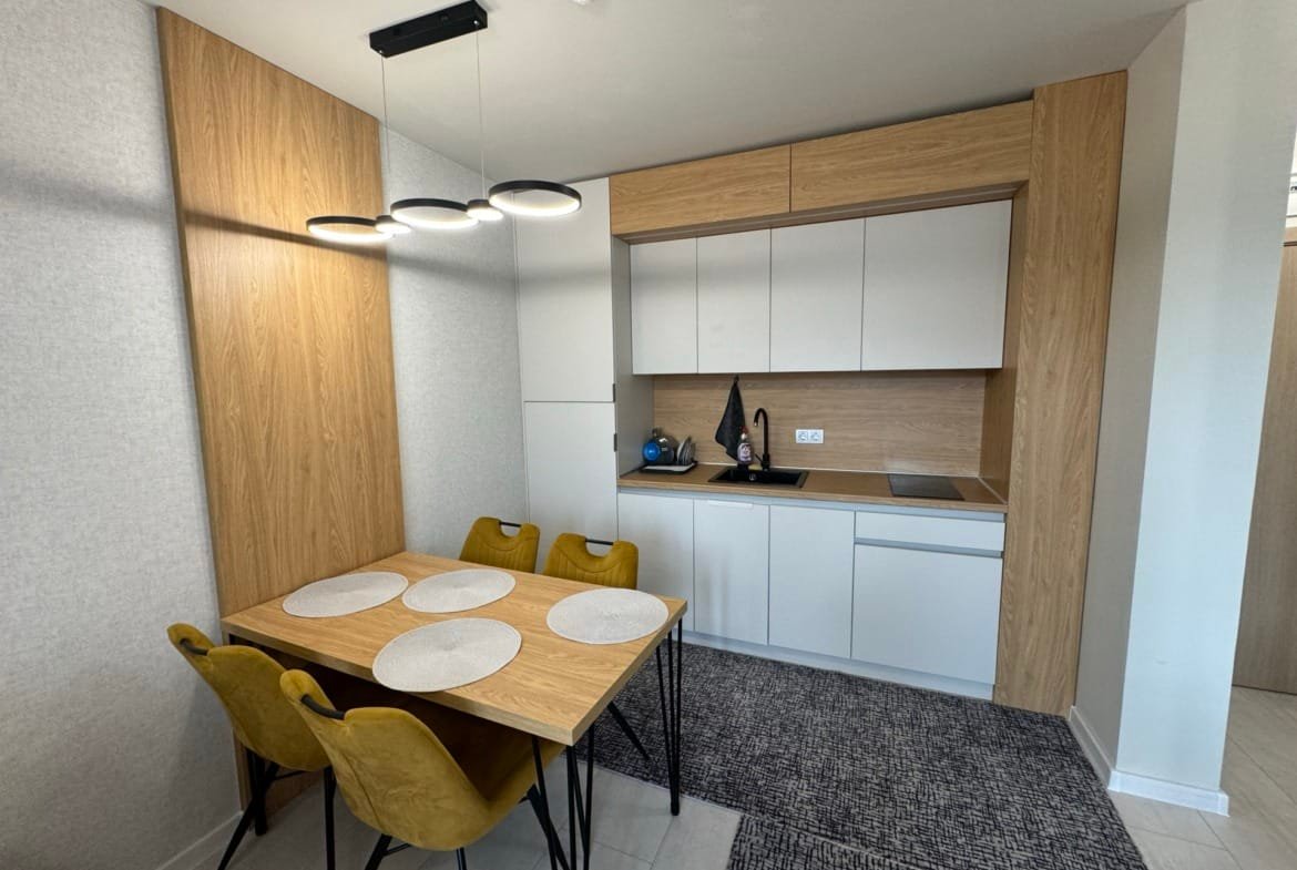 Современная кухня с деревянными элементами, желтыми стульями и обеденным столом, отражающая стиль жизни в Болгарии.