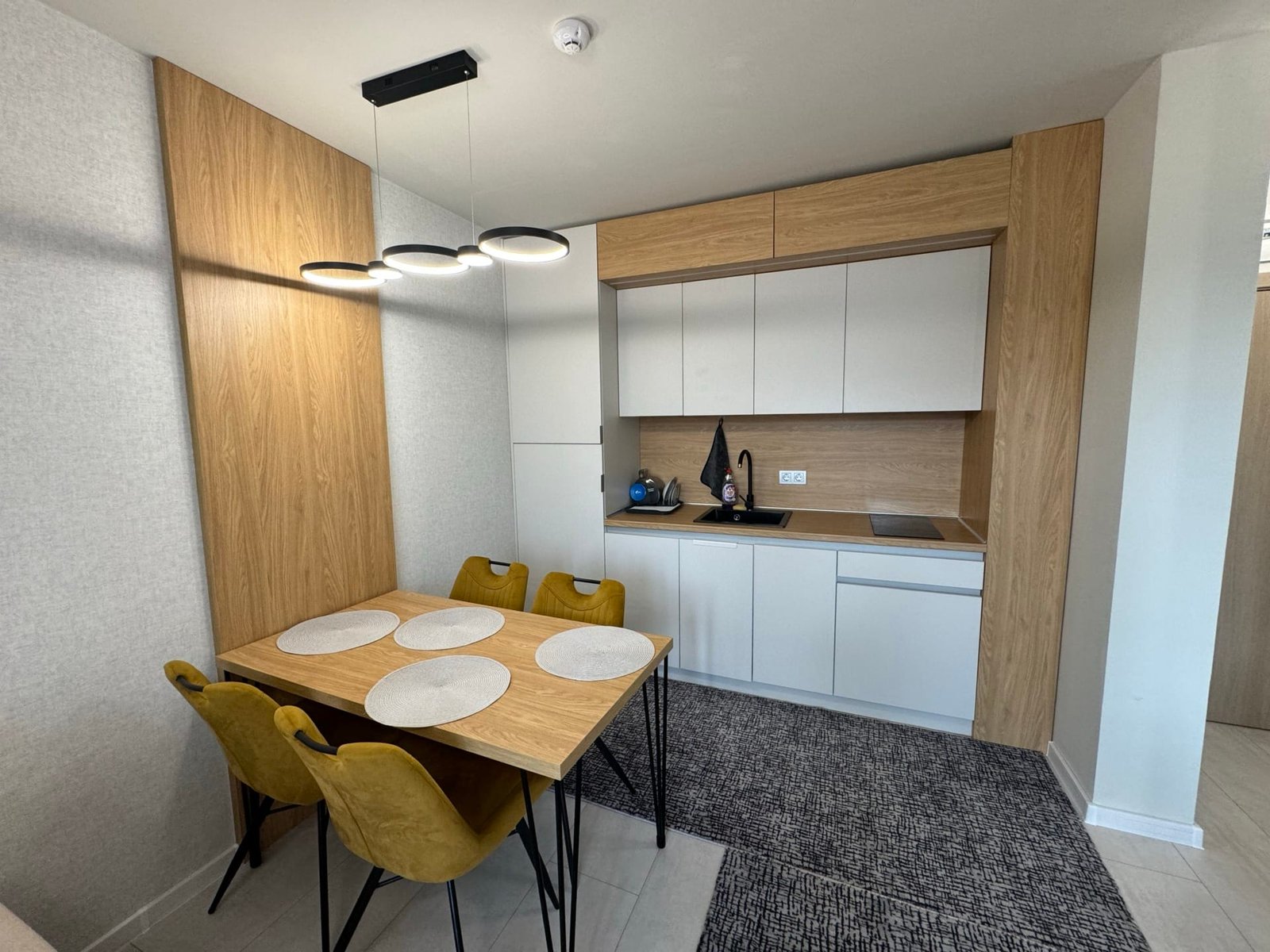 Современная кухня с деревянными элементами, желтыми стульями и обеденным столом, отражающая стиль жизни в Болгарии.