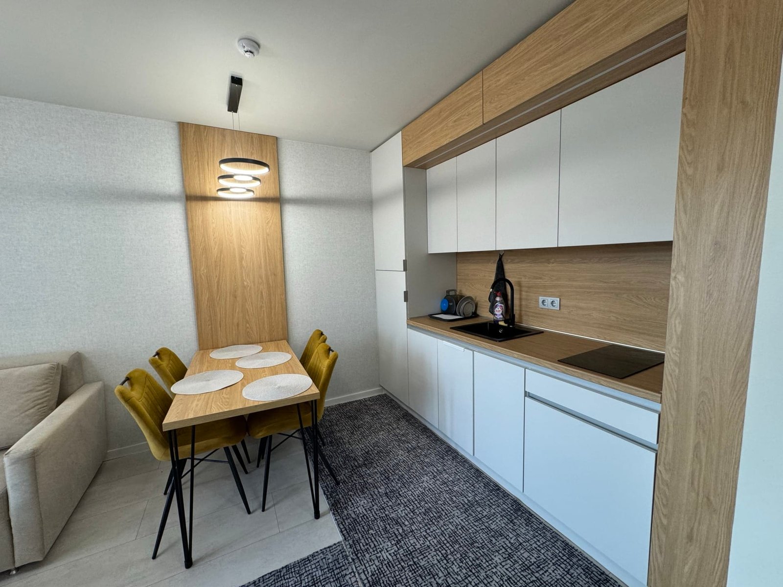 Современная кухня с обеденной зоной, светлым интерьером и деревянными элементами в квартире для продажи в Болгарии.