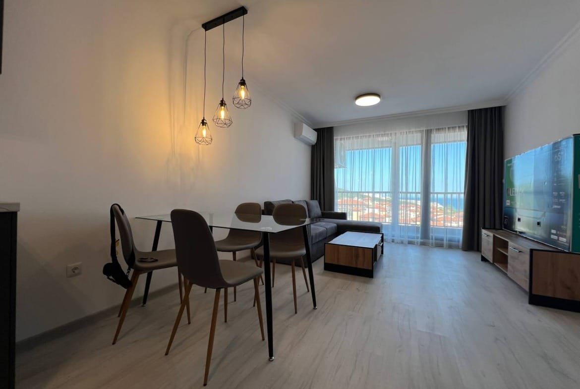 Современный интерьер квартиры в Болгарии с комфортной мебелью, стеклянным столом и панорамным видом на город.