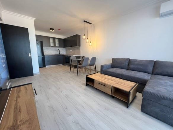 Современная гостиная с кухней, стильная мебель, обеденная зона и светильники, идеальная для покупки недвижимости в Болгарии.