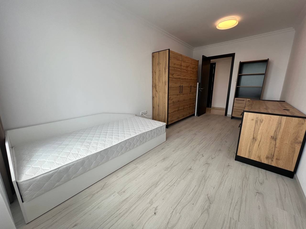 Светлая комната с кроватью, шкафом и тумбой, готовая для продажи или аренды недвижимости в Болгарии.
