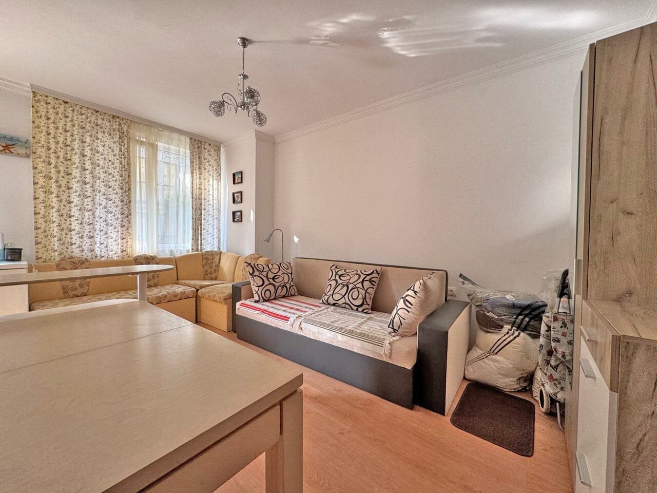 Современная гостиная с диваном и уютными мягкими креслами, расположенная в квартире для продажи, предлагает комфорт и светлое пространство.