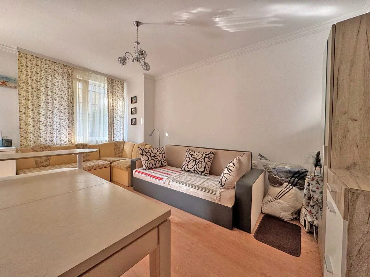 Современная гостиная с диваном и уютными мягкими креслами, расположенная в квартире для продажи, предлагает комфорт и светлое пространство.