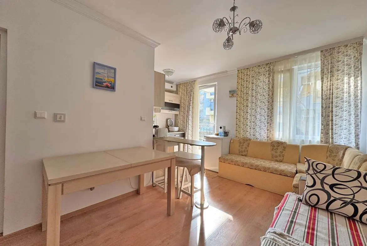 Современная гостиная с мягким диваном, столом и кухонной зоной, идеальная квартира для проживания в Болгарии.