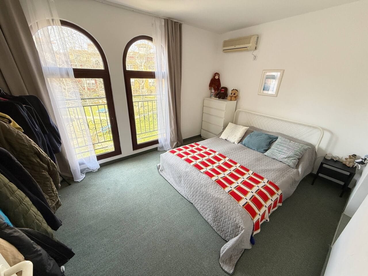 Современная спальня с уютной атмосферой и балконными окнами Уютная спальня с двуспальной кроватью, выход на балкон, светлые тона, рядом с жильем на Солнечном берегу.