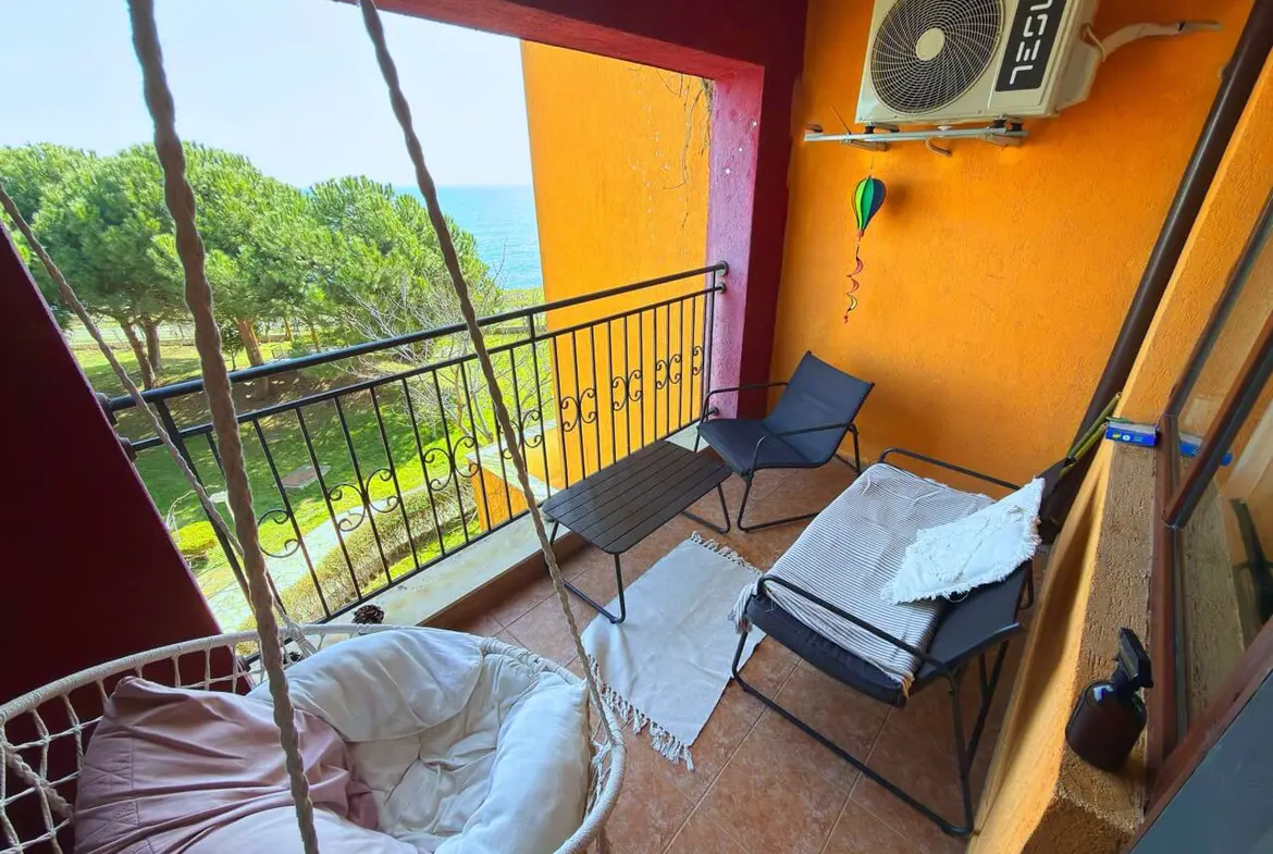 Уютная терраса с видом на море, со стильной мебелью и качелей, идеально подходит для отдыха в апартаментах.