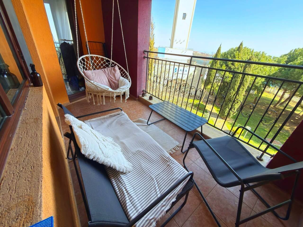 Уютный балкон с висячим креслом и видом на природу Тераса с уютной мебелью, видом на зелень и пространство для отдыха. Идеальное место для создания комфортного жилья в Болгарии.