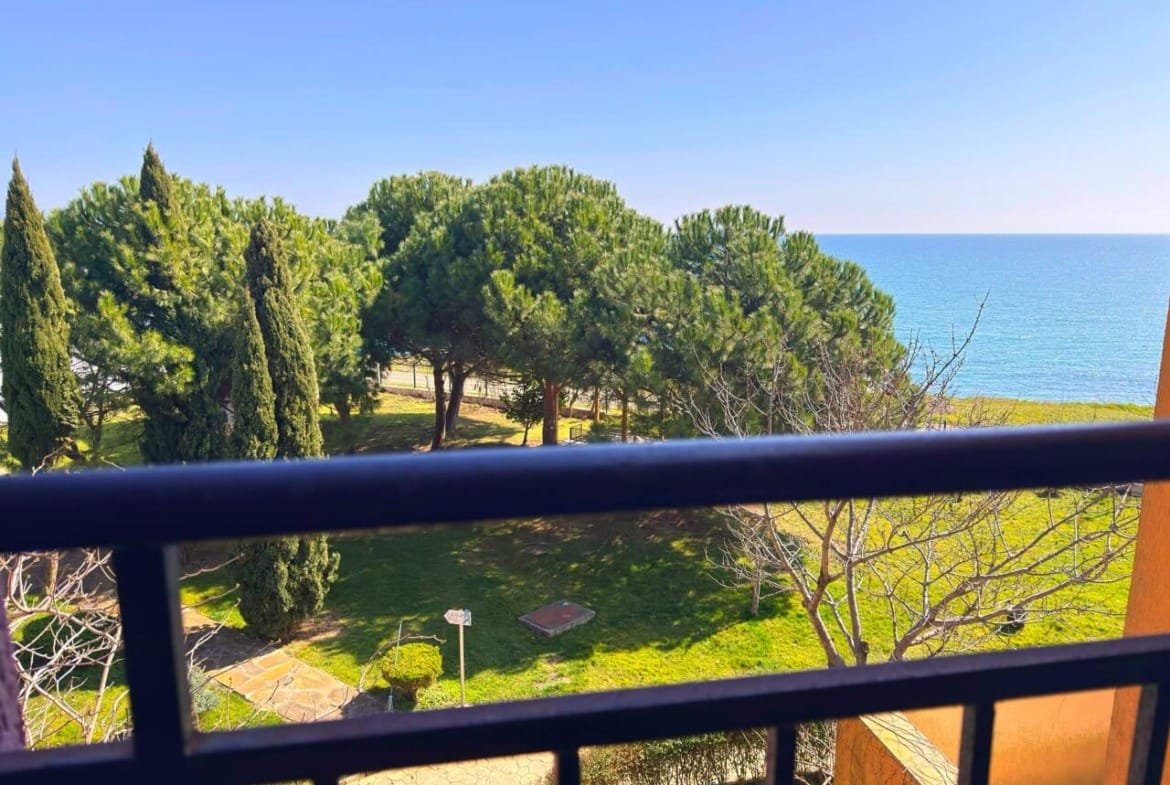 Вид с балкона на море и зелёные деревья, рядом с апартаментами у моря в Болгарии, идеальные условия для жизни.