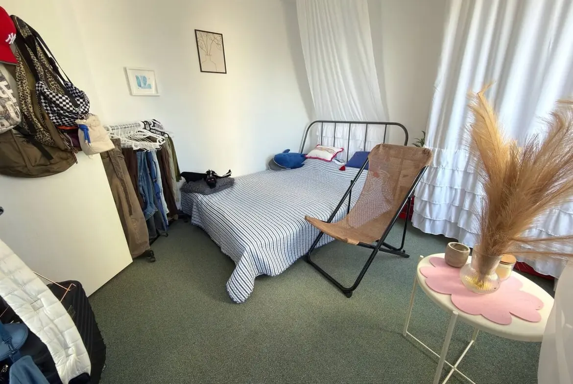 Уютная спальня с двуспальной кроватью, уютной мебелью и естественным светом, идеальна для проживания в Болгарии.