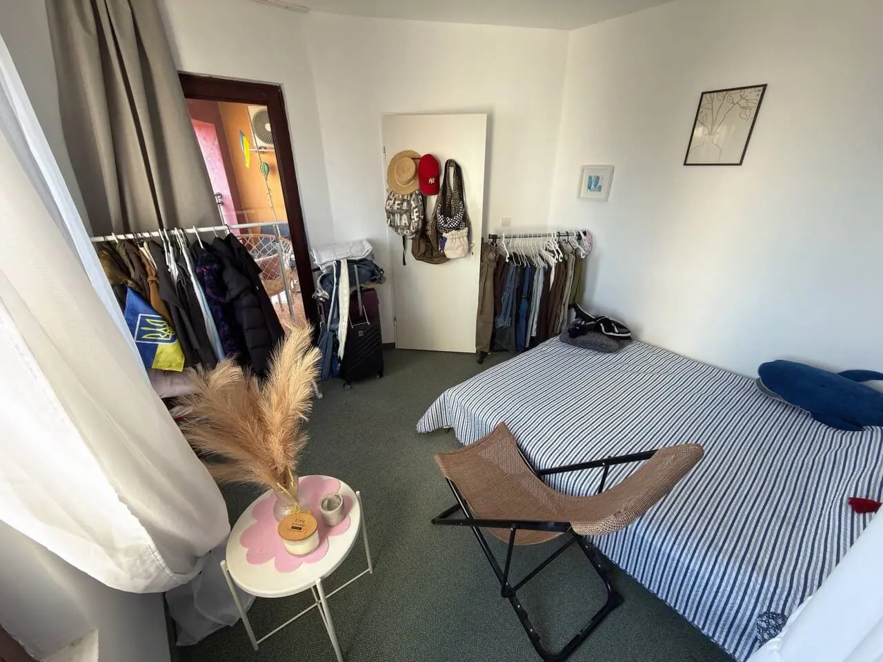 Уютная спальня с двуспальной кроватью, стилизованная в светлых тонах, с гардеробом и зоной для отдыха в квартире у моря.