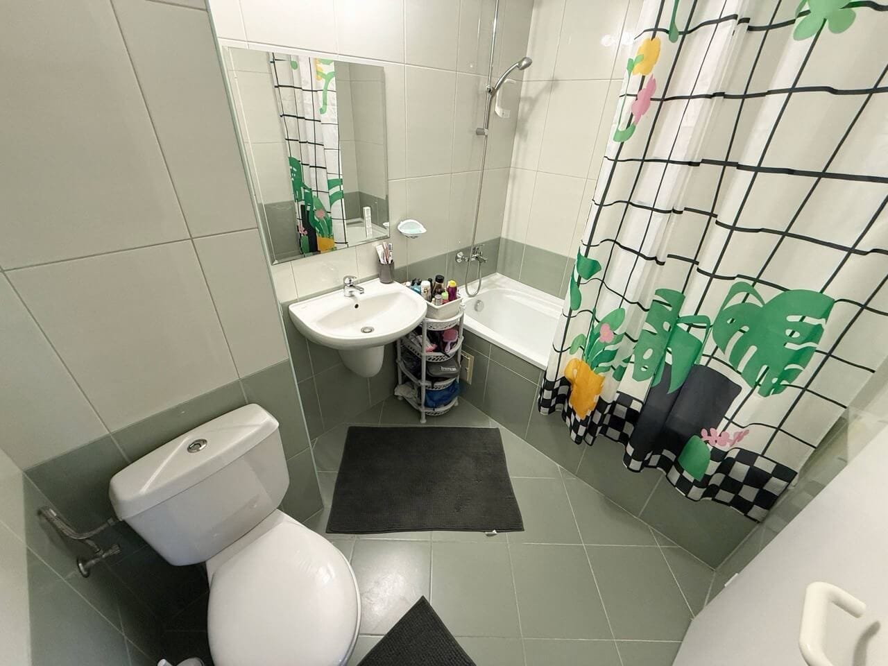 Современная ванная комната с душевой и ярким занавесом Современная ванная комната с душевой кабиной и ванной, белой сантехникой и ярким занавесом с растительным узором.