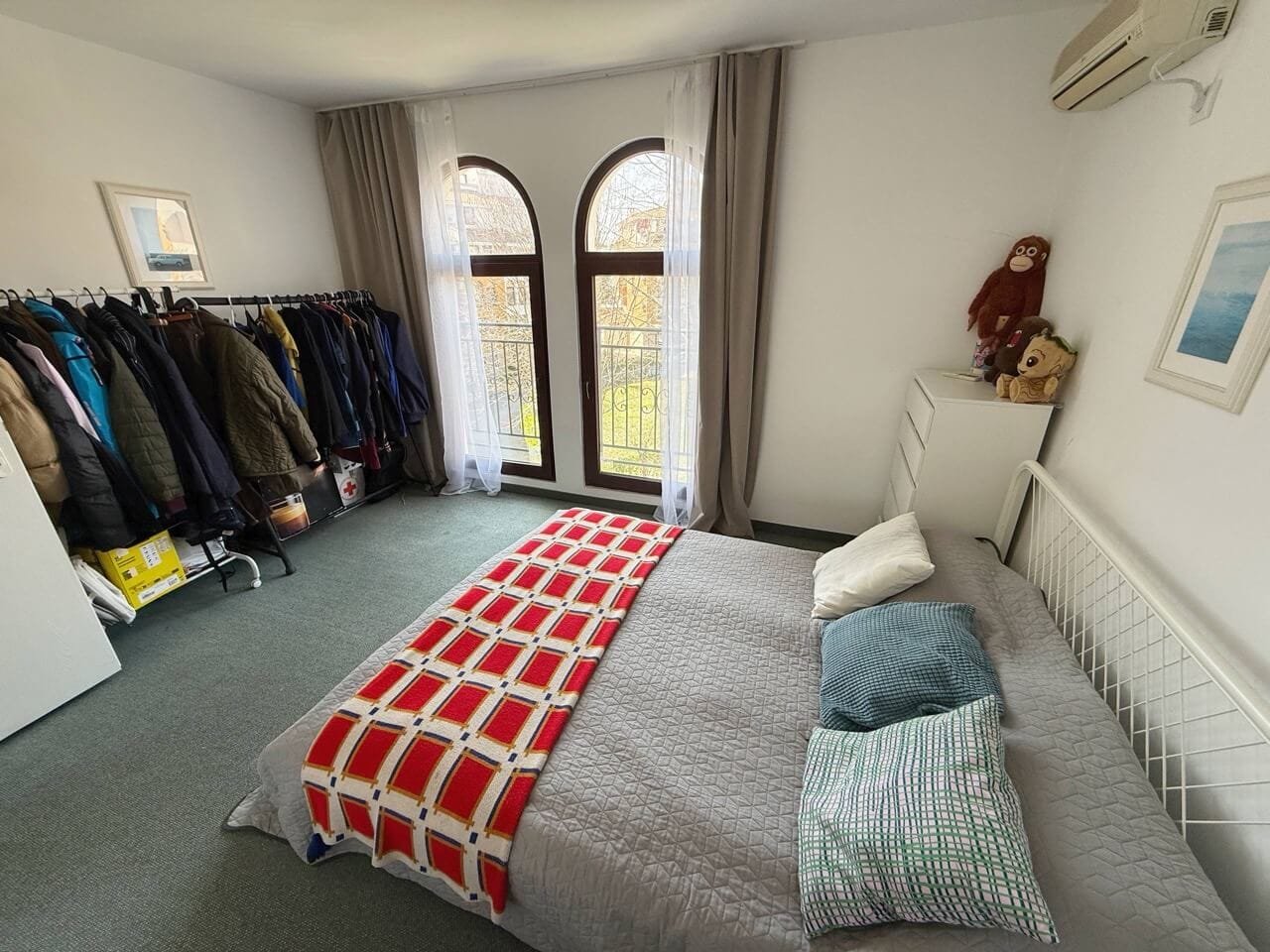 Современная спальня с удобной кроватью и гардеробом Светлая спальня с двуспальной кроватью и гардеробом, большие окна с видом на улицу, уютный текстиль и стильный интерьер.