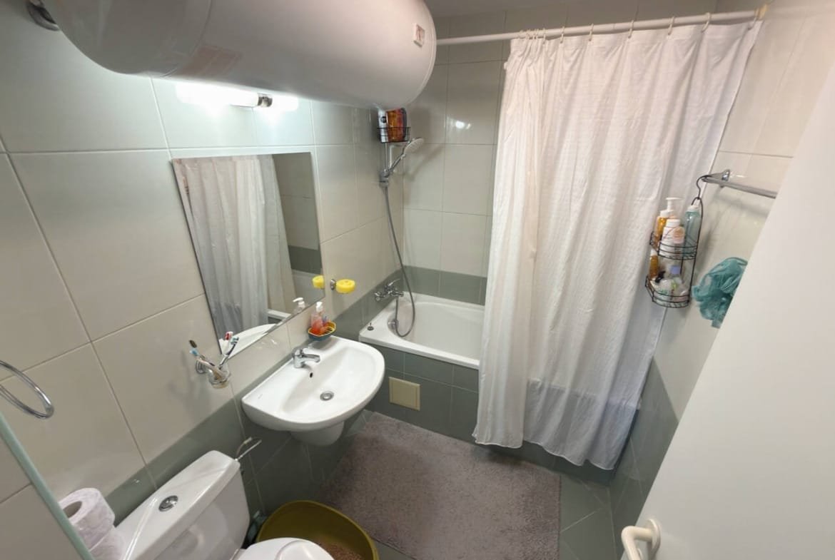 Современная ванная комната с ванной, душевой занавеской и раковиной, акцент на чистоту и функциональность, идеальна для жилья в Бургасе.