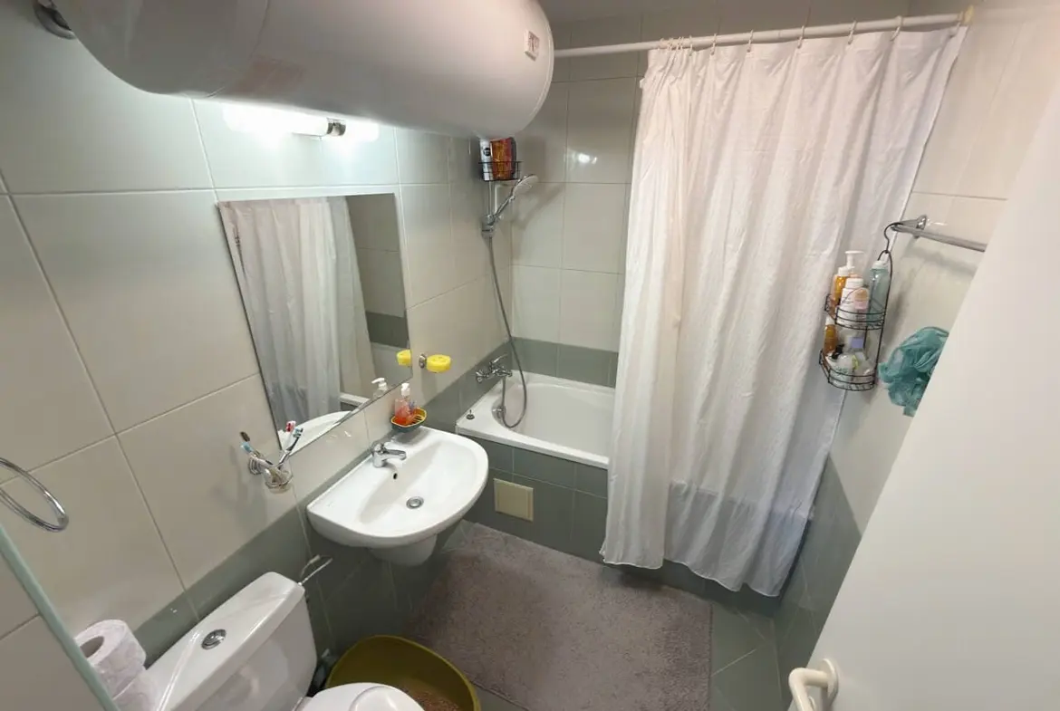 Современная ванная комната с ванной, душевой занавеской и раковиной, акцент на чистоту и функциональность, идеальна для жилья в Бургасе.