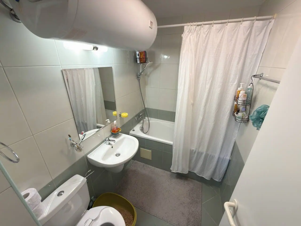 Современная ванная комната с ванной, душевой занавеской и раковиной, акцент на чистоту и функциональность, идеальна для жилья в Бургасе.